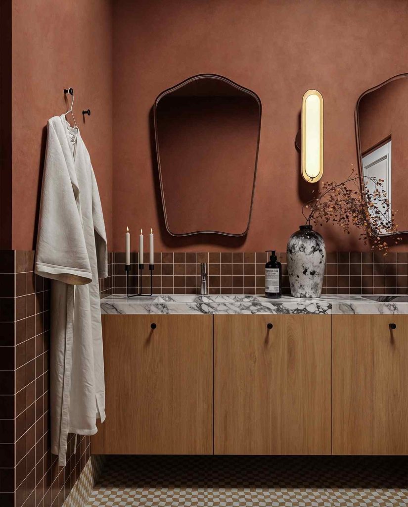 Terracotta bathroom with marble countertops and a unique mirror.
