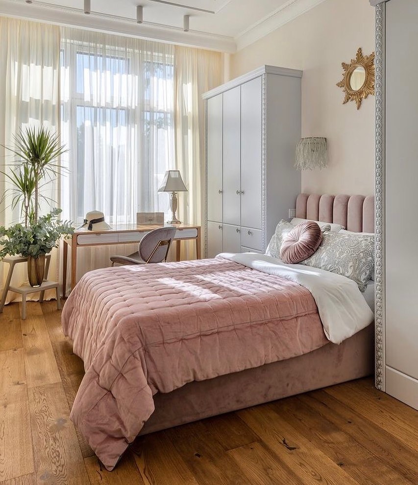 Blush pink velvet bed with natural light and greenery by the window.