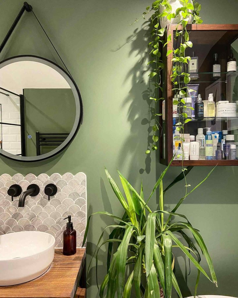 Bathroom with green walls, black fixtures, and hanging plants for a fresh look.
