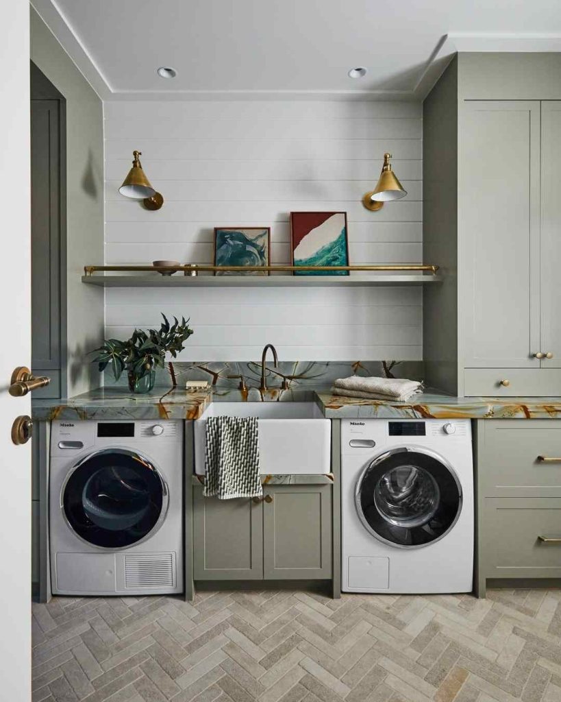 Sage green laundry room with a marble countertop and brass accents.
