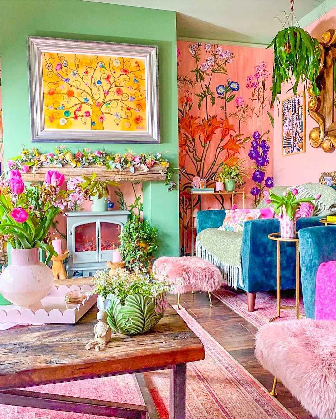 Floral-themed living room with pink poufs, green walls, and vibrant decor.
