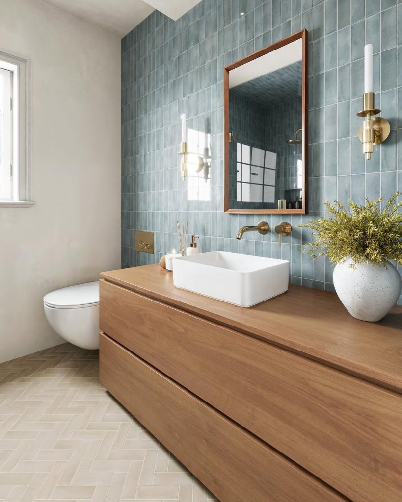 Blue tile bathroom with a warm wooden vanity and brass fixtures.
