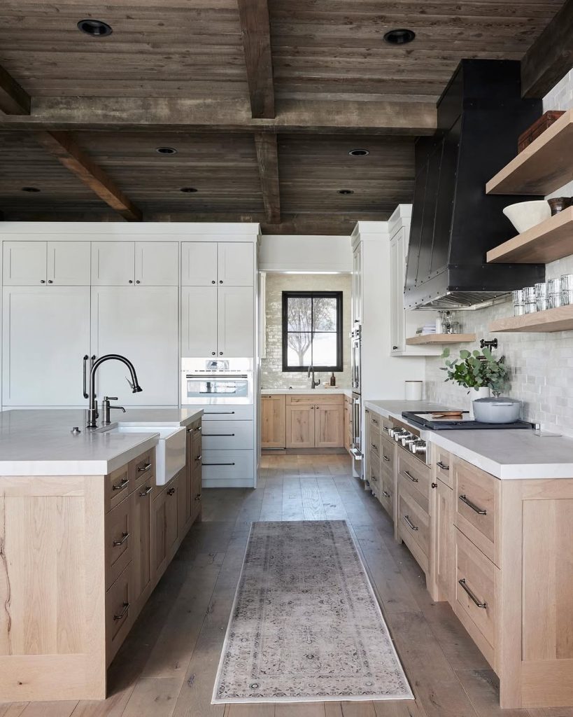 Minimalist rustic kitchen with natural wood tones, white cabinets, and a rugged wooden ceiling.
