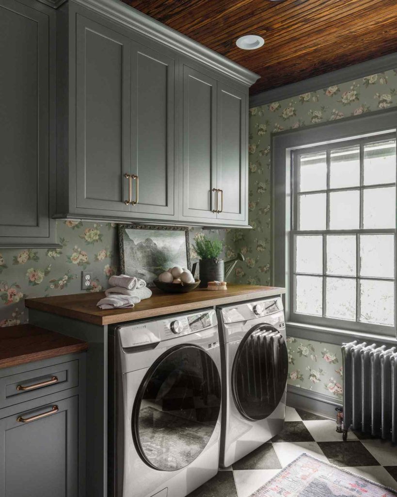 Cottage-style laundry room with blue cabinets, floral wallpaper, and wood accents.
