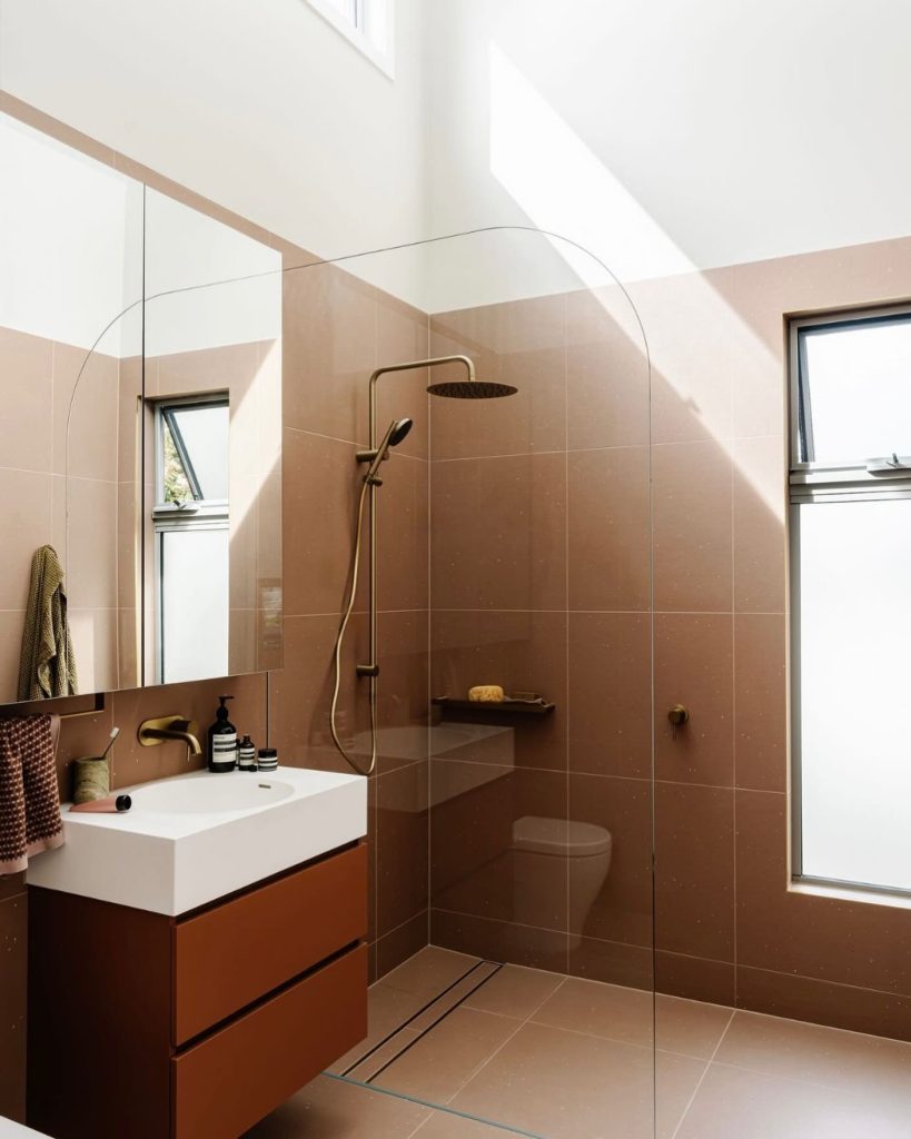 Terracotta-tiled shower with minimalist brass fixtures.
