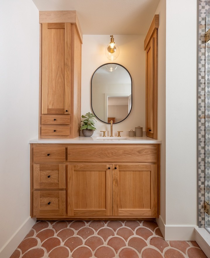 Bathroom with a natural wood vanity and terracotta floor tiles.
