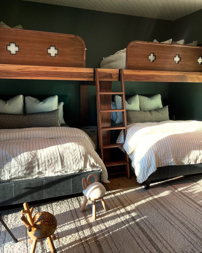 Cozy bunk bed setup with wooden frames, striped bedding, and adorable animal stools in a dorm room.
