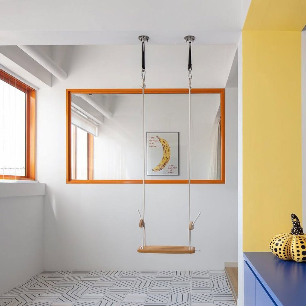 Minimalist indoor swing with colorful accents in a bright room.
