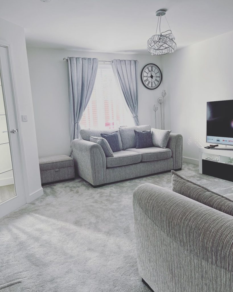 Soft grey living room with matching sofas and textured carpet.
