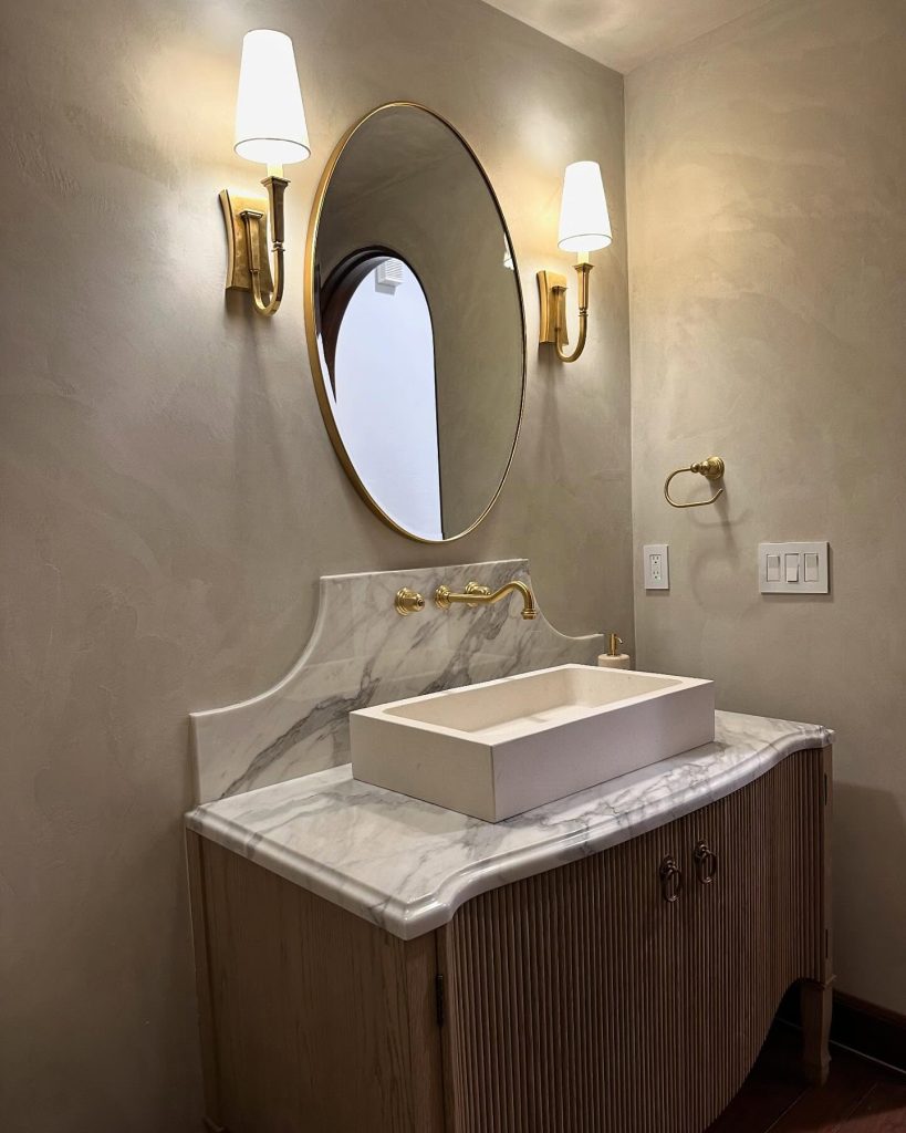 Elegant marble shower with gold accents and arched window