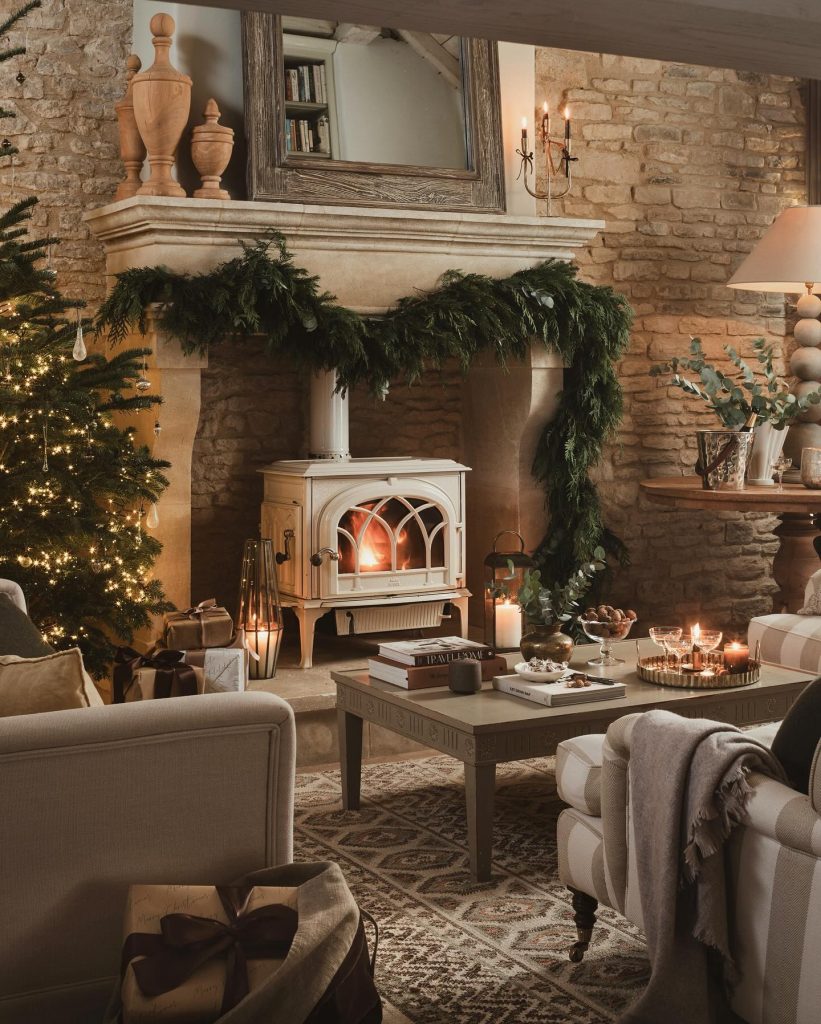 Rustic fireplace with garland and wood-burning stove in a cozy stone living room.
