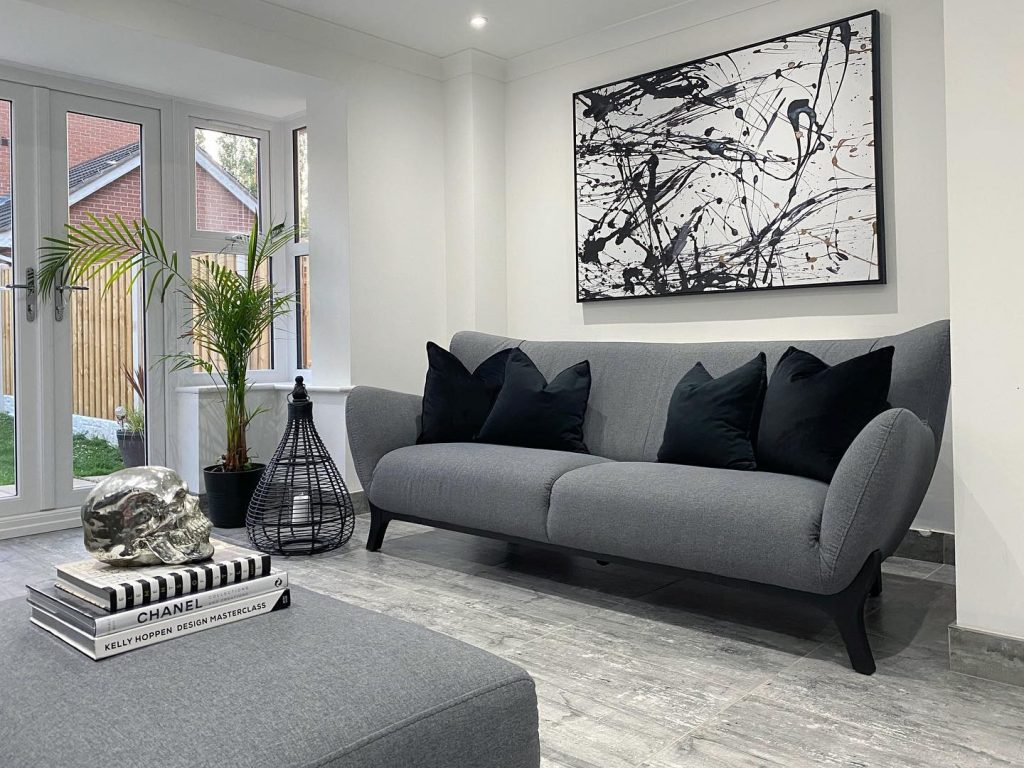 Modern grey sofa with black pillows and bold abstract wall art.
