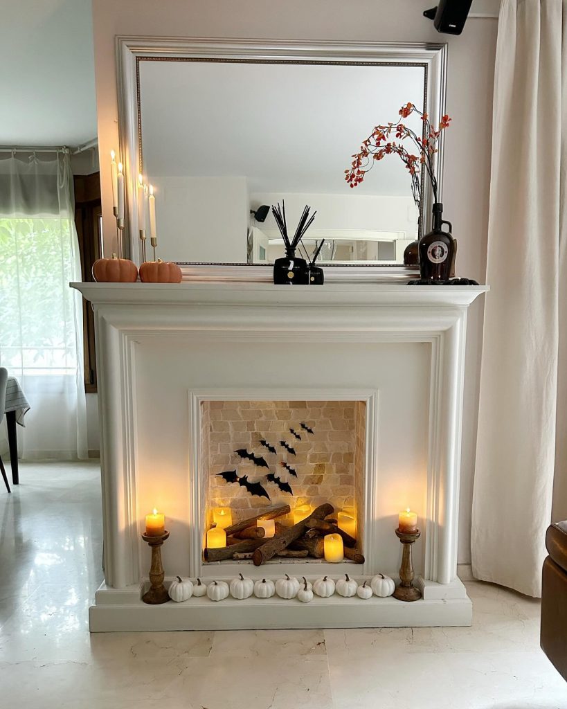 Halloween-inspired fireplace with bats, candles, and pumpkins.
