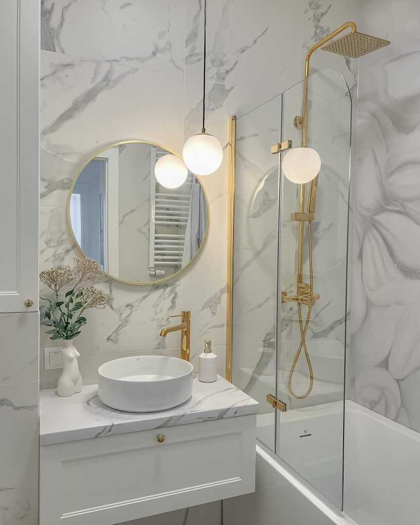 Compact bathroom with soft marble walls and modern gold fixtures