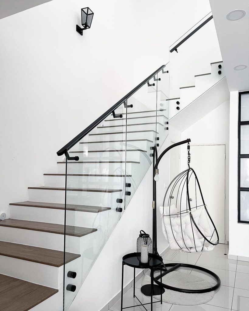 Stylish hanging chair with white cushions in a glass stairwell.
