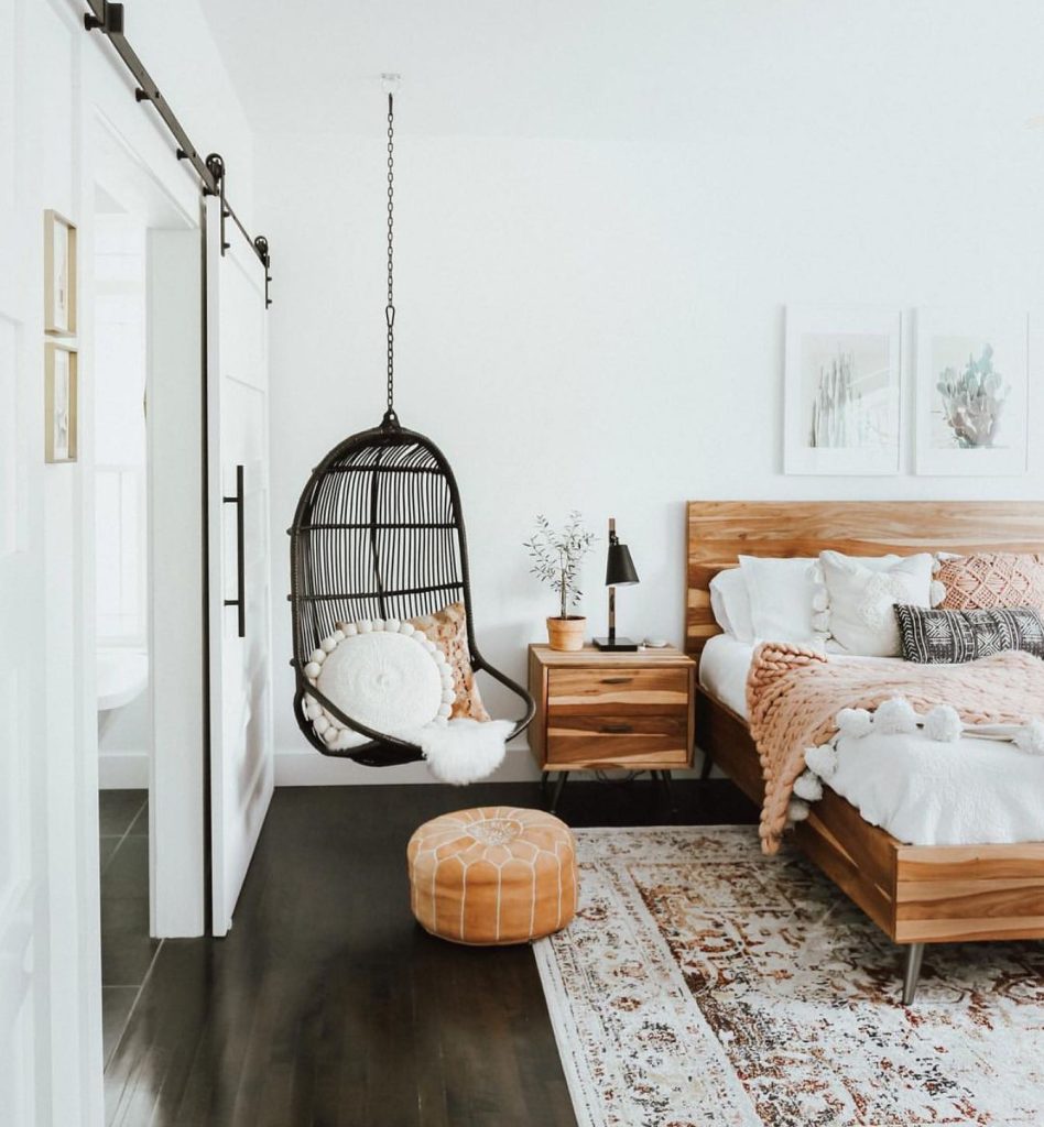 Boho black wicker swing in a serene bedroom retreat.
