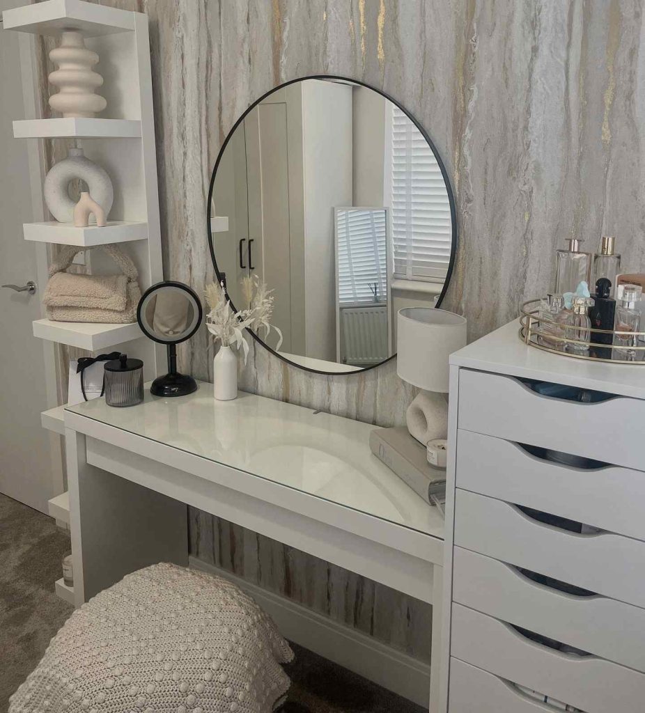 Sleek white vanity with a round mirror and artistic decor pieces.
