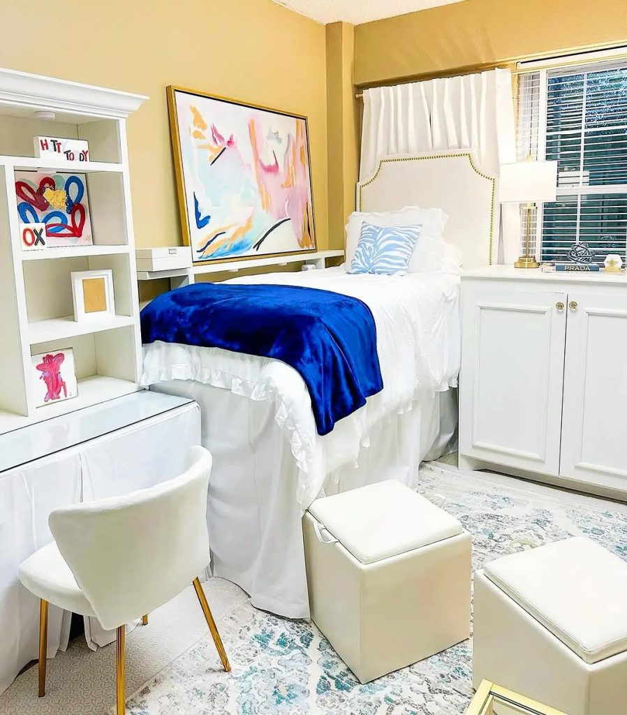 Neutral and bold dorm featuring a vibrant blue throw, abstract art, and elegant furniture.
