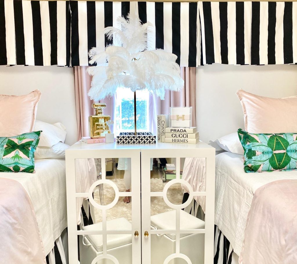 Glamorous dorm with bold black-and-white stripes, tropical pillows, and a mirrored cabinet.
