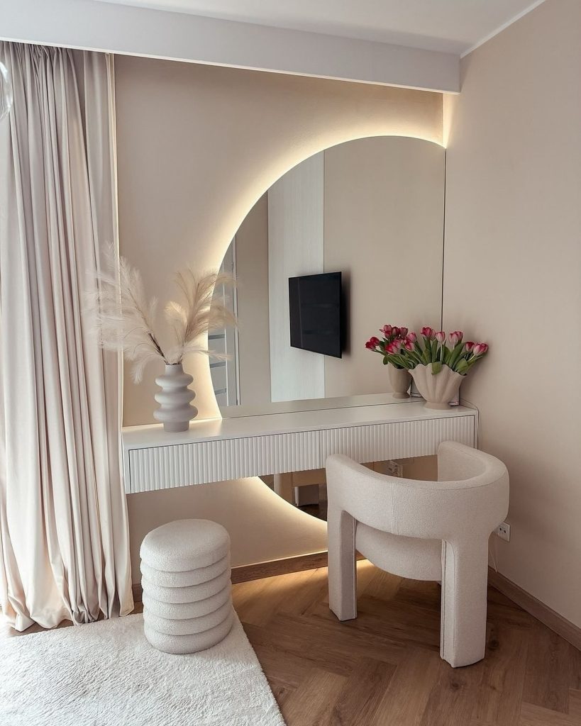 Modern dressing room with a glowing curved mirror and soft textures.
