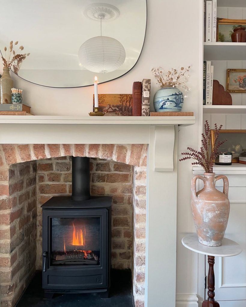 Modern rustic fireplace with stacked stone and a wooden mantel.
