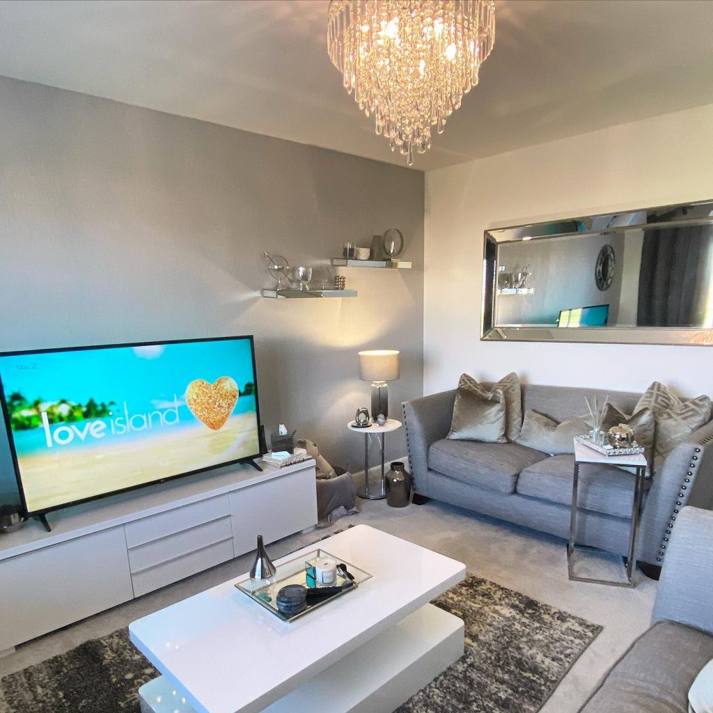 Glamorous grey living room with mirrored decor and chic white furniture.
