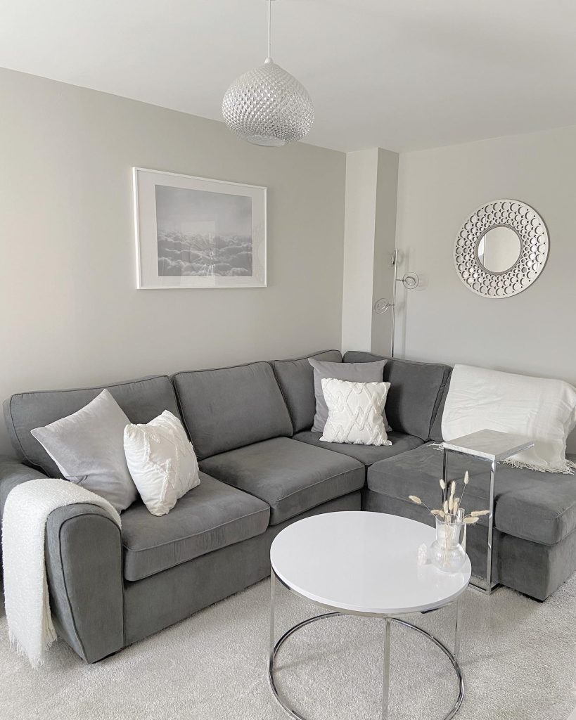 Minimalist grey sectional with clean white accents and metallic decor.
