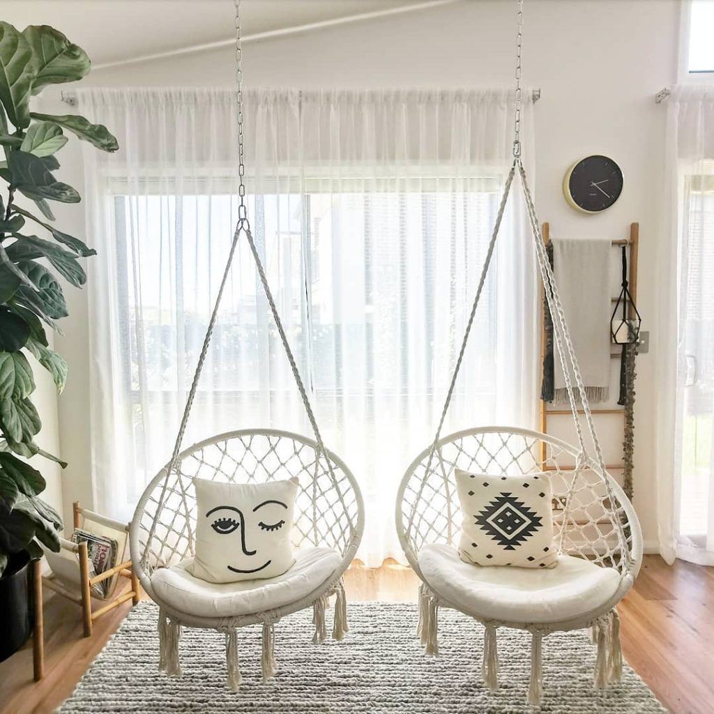 Boho twin hanging chairs with macramé details and cozy cushions.
