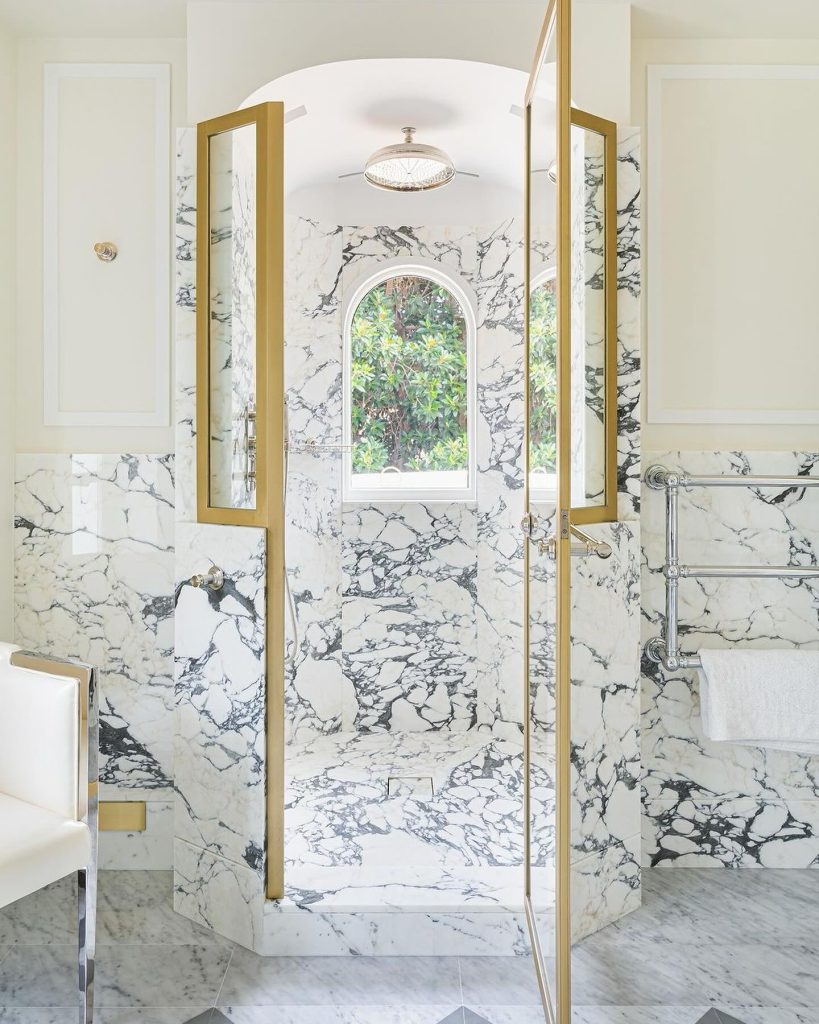 Classic black and white marble shower with gold details and seating