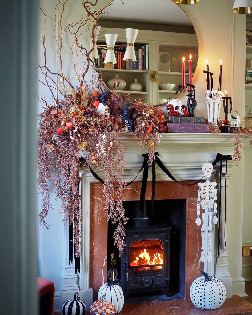 Halloween-themed fireplace with bats, pumpkins, and dried florals.
