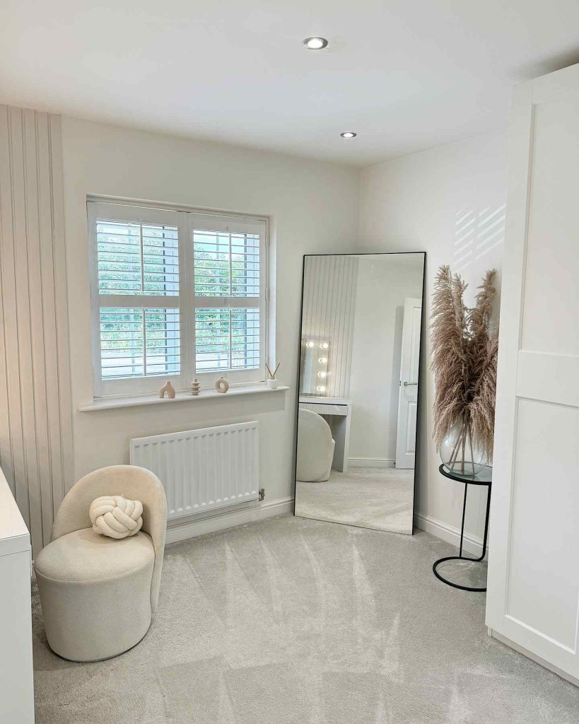 Bright dressing area with a large floor mirror and pampas grass.
