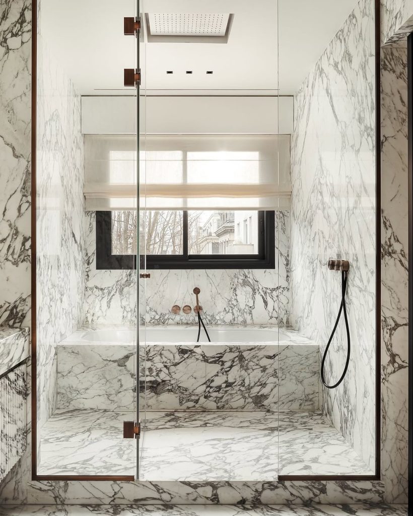 Modern marble bathtub and shower with floor-to-ceiling veining.