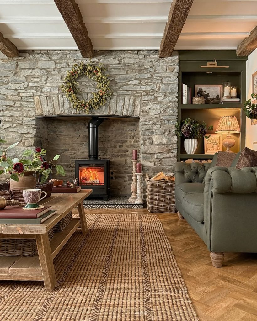 Stone fireplace with a wood-burning stove and floral wreath in a rustic living room.
