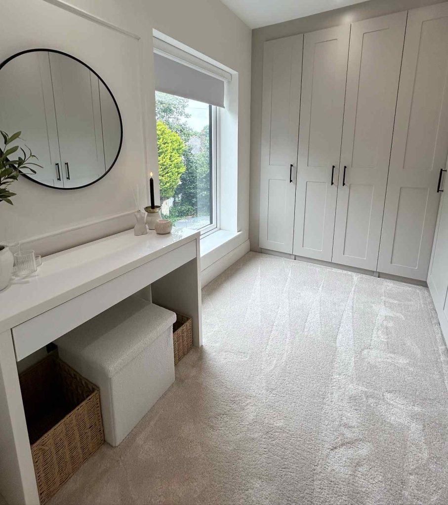 Sleek storage dressing room with natural light and a round mirror.
