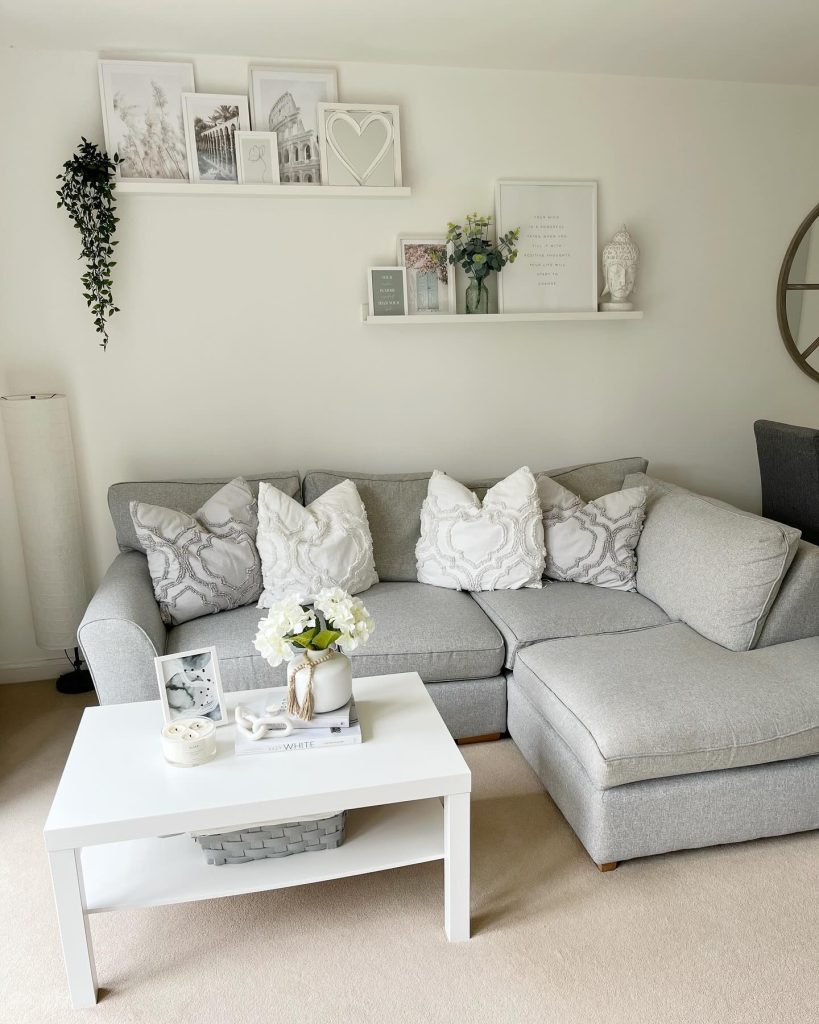 Bright grey living room with gallery shelves and a white coffee table.
