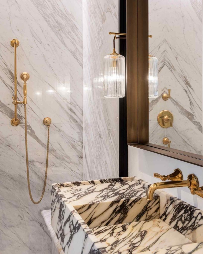 Bold marble vanity with gold fixtures and glass pendant lighting