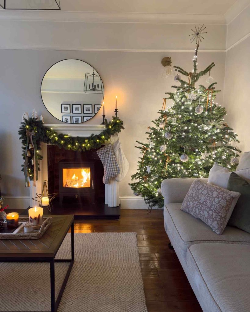 Festive fireplace with garland, stockings, and a glowing Christmas tree.
