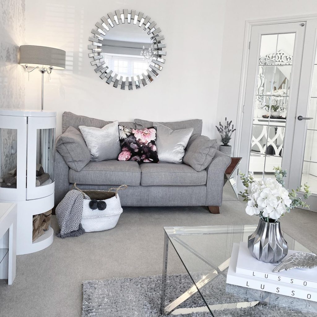 Glamorous grey sofa with metallic accents and a crystal chandelier.
