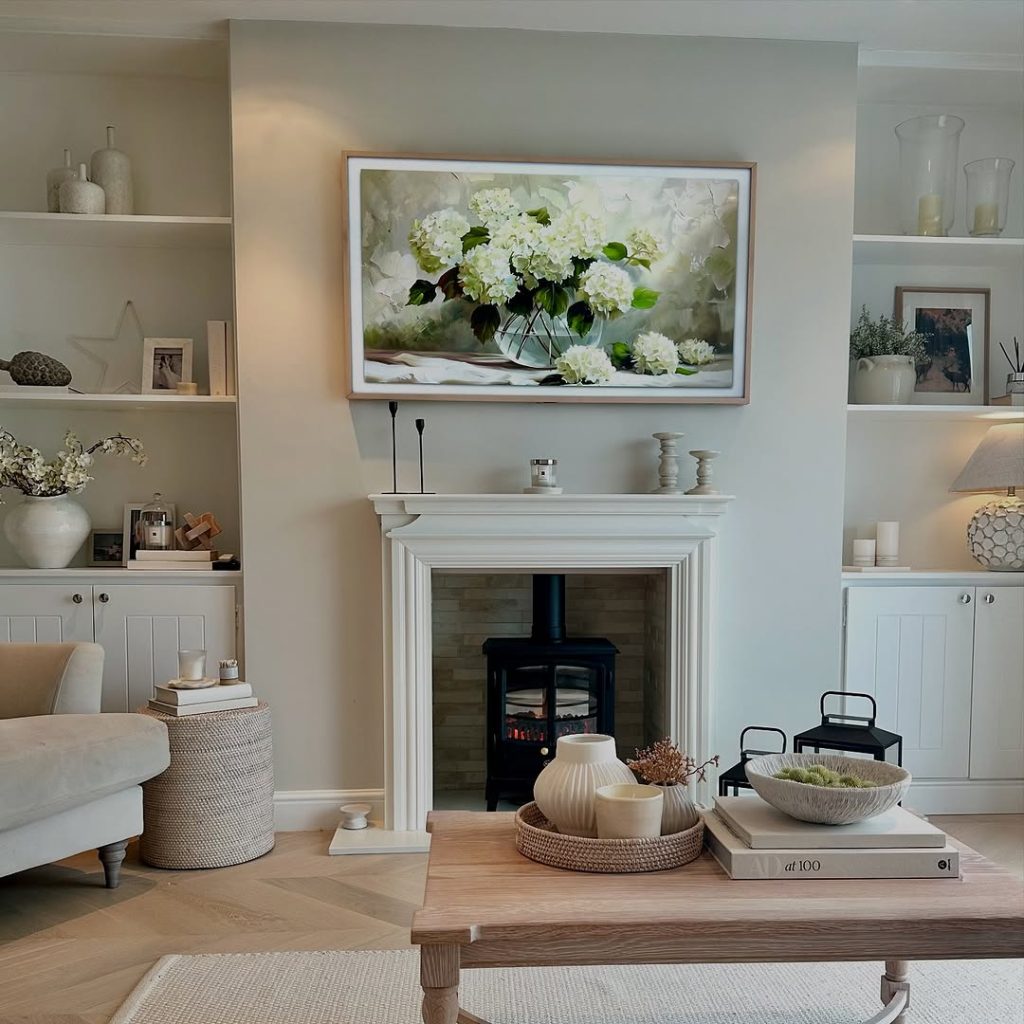 Elegant white fireplace with floral artwork and curated neutral decor.
