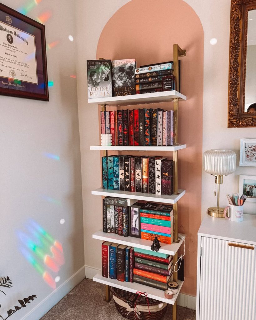 A bookshelf filled with various books stands beside a mirror in a cozy room setting.