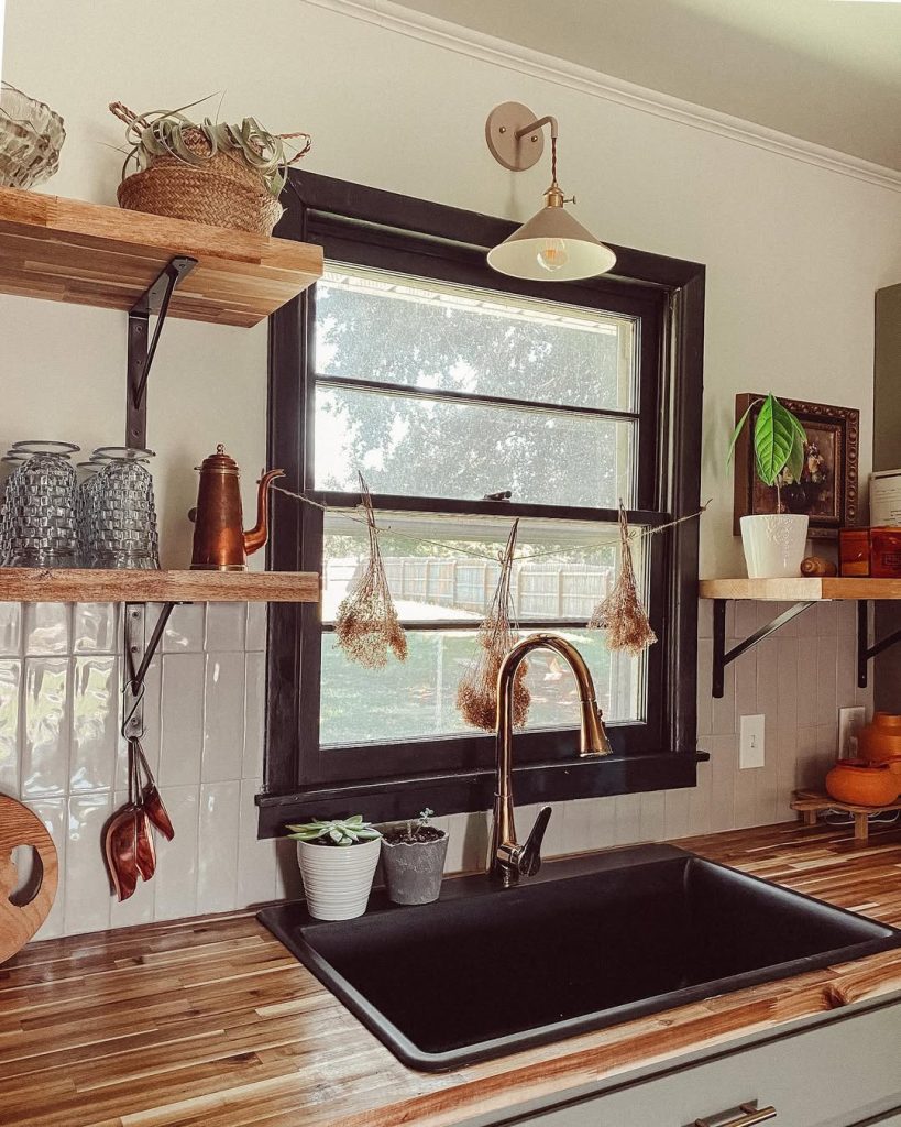 Rustic boho kitchen with open wooden shelves and black sink.
