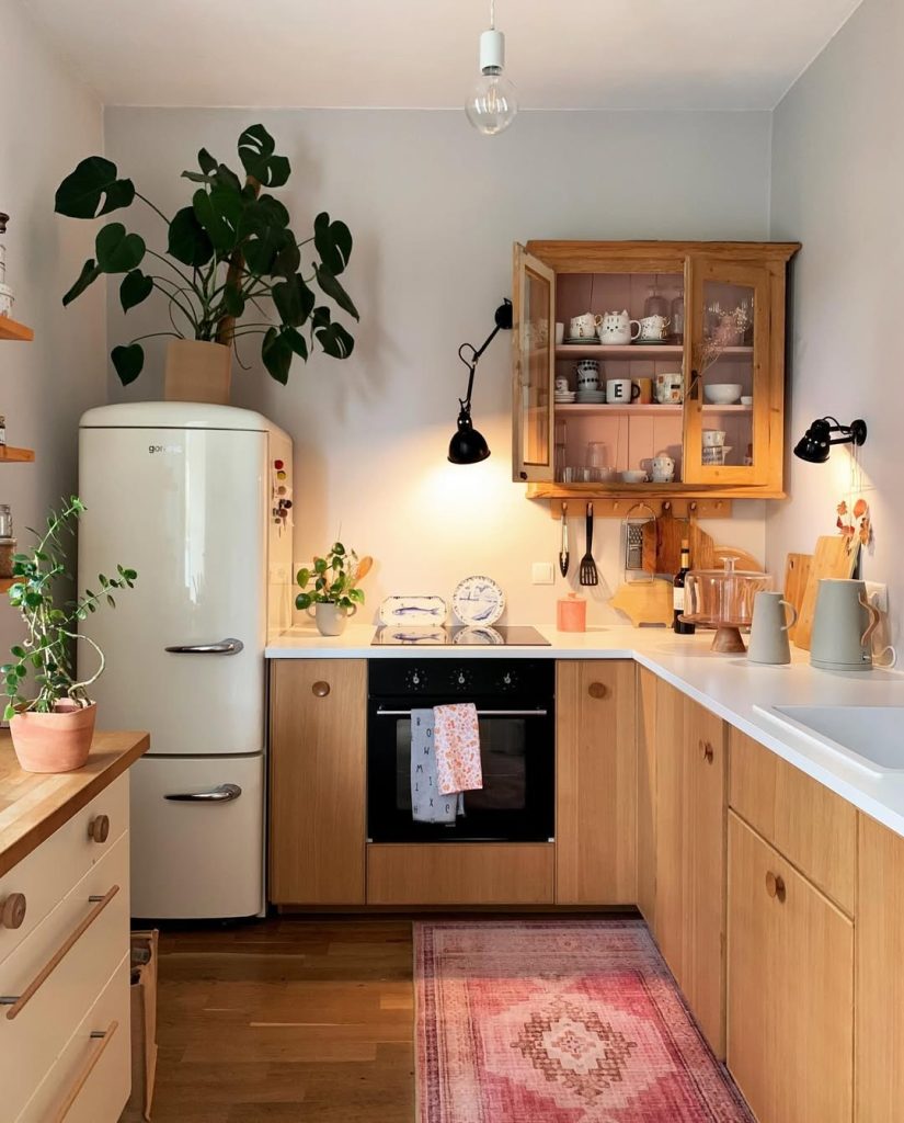 Rustic cozy kitchen with wood cabinets, vintage fridge, and warm lighting.
