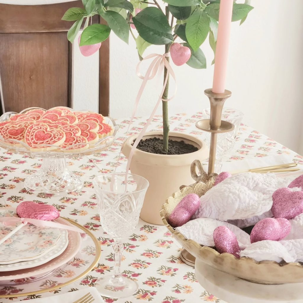 Soft pastel romantic table for two with glittery hearts and sweet treats.
