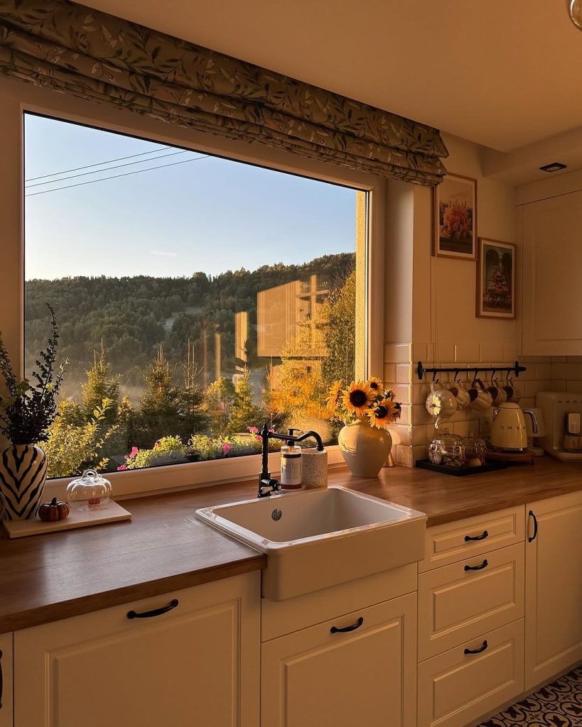 Farmhouse cozy kitchen with a large window view, wooden countertops, and soft lighting.
