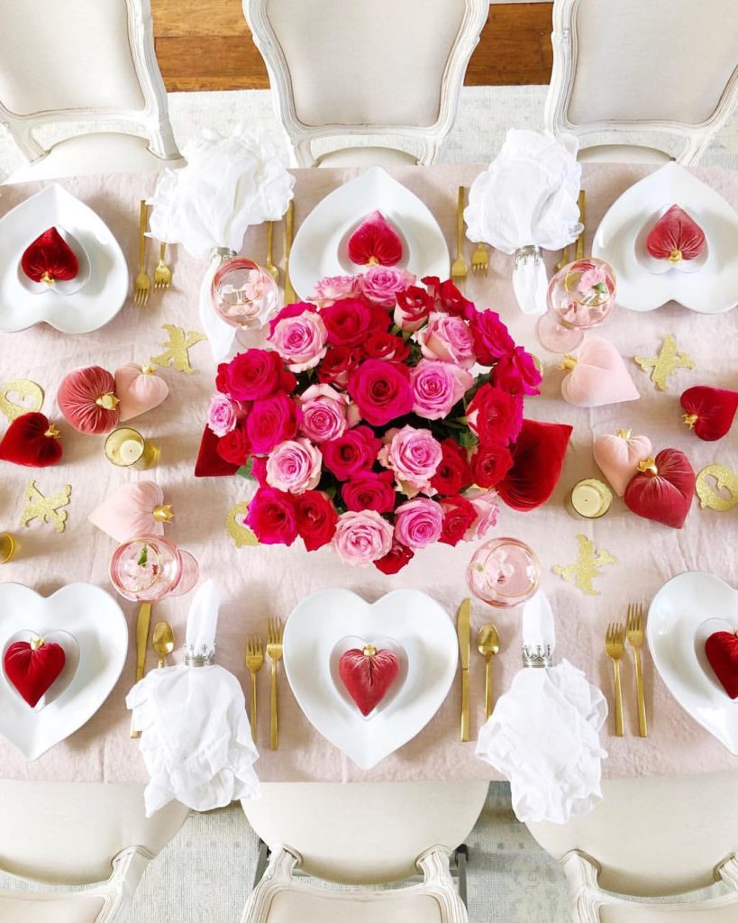 Blooming romantic tablescape with vibrant roses and heart-shaped dinnerware.
