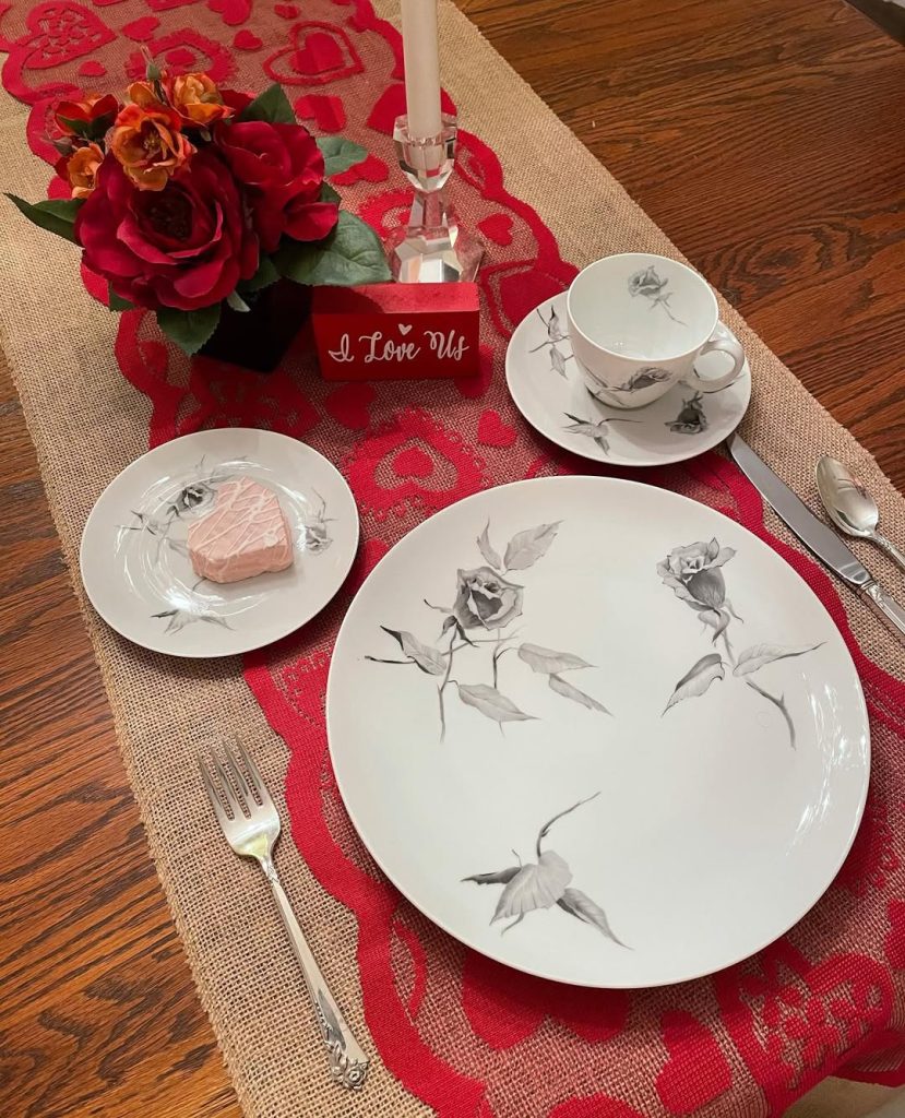 Rustic charm meets romance with elegant floral dinnerware and a red rose centerpiece.
