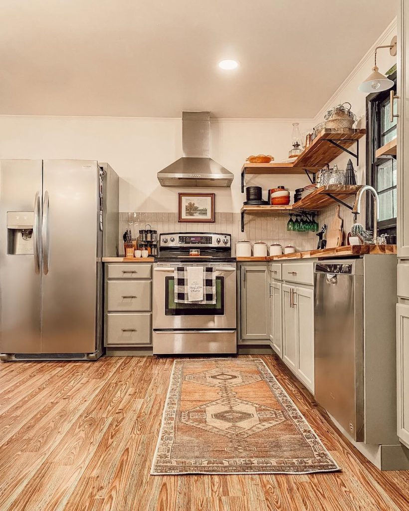 Rustic modern boho kitchen with sage green cabinets and warm lighting.
