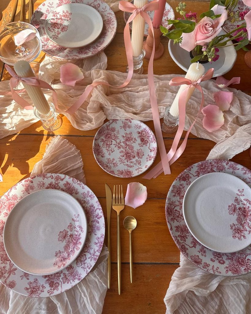 Soft floral romantic table for two with pastel ribbons and gold flatware.
