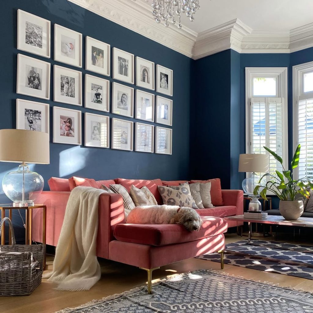 Nautical-inspired navy blue wall with sailboat artwork and light wood furniture.