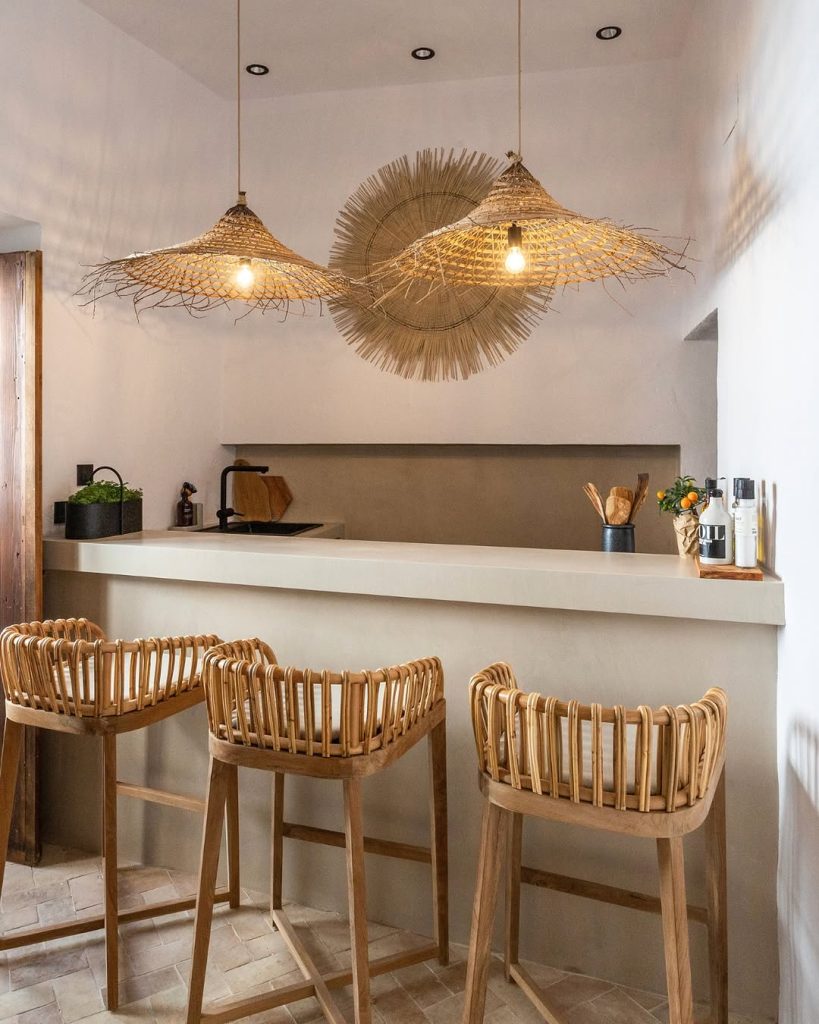 Minimalist boho kitchen with rattan chairs and woven pendant lights.
